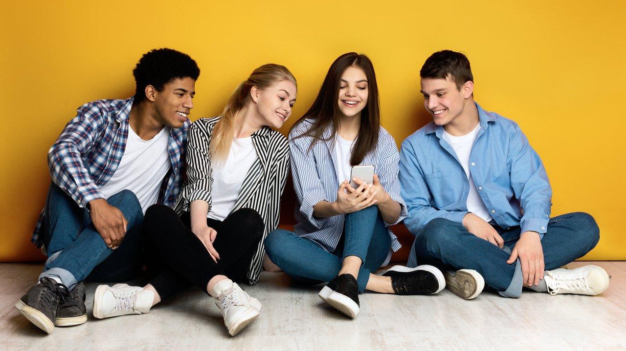 Jeunes multiethniques utilisant leur smartphone pour partager leurs stories sur les réseaux sociaux.