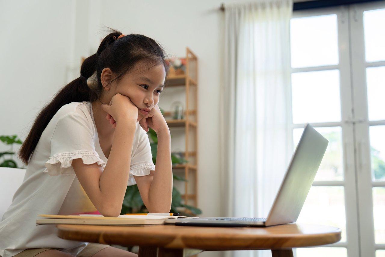 Une étudiante concentrée en apprentissage en ligne à domicile, utilisant un ordinateur portable dans un environnement calme.